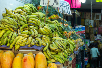 Abundant Tropical Fruit Display with Green Plantains and Papayas at Market © sandor