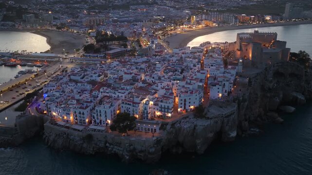 Spanish resort town of Peniscola in Valencia Provence, drone evening shot with night illumination of Peniscola castle. Vacation in Spain