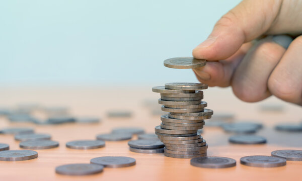 Hand Stacking Coins on Table for Savings Growth and Financial Planning Concept