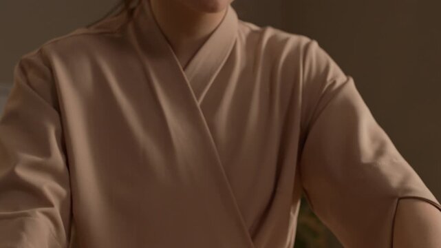 Tilt down close up of young Caucasian female therapist massaging male client back with wooden roller in cozy treatment room