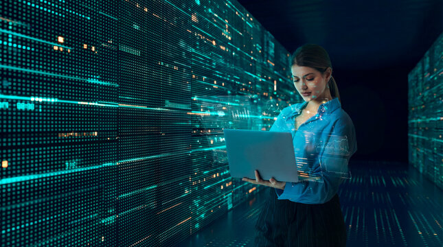 Data analyst woman working on laptop with real time metrics in digital data corridor