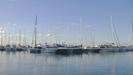 Fototapeta premium Luxury yachts and sailboat masts reflecting in calm blue water. Abstract nautical background for travel, charter, waterfront real estate and lifestyle branding.
