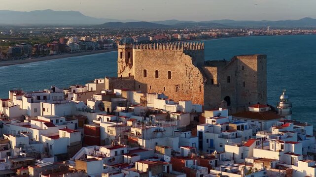 Peniscola castle drone shot, sunset view of Peniscola historic Spanish resort, vacation on Costa del Azahar, Spain, orbiting close up drone shot of Peniscola at sunset