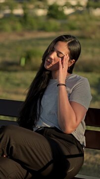 Young woman suffering from a headache and feeling stressed while sitting in a park