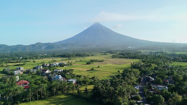 Drone perspective captures Mount Mayon above vibrant rice paddies. Ideal for travel destination.