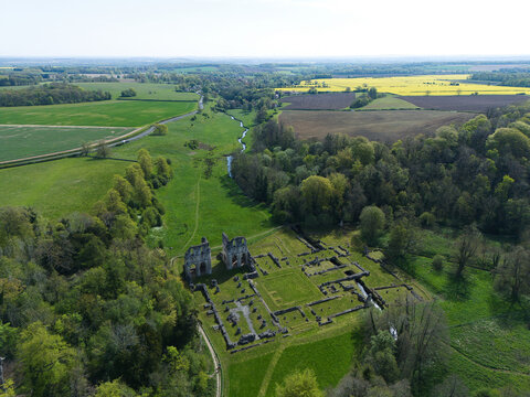 Historic ruins of Roche Abbey surrounded by green valley meadows and woodland, aerial view, UK.