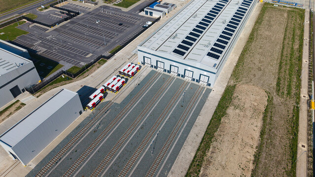 Locomotive manufacturing factory with rail tracks leading into workshop doors, aerial view, Goole, UK.