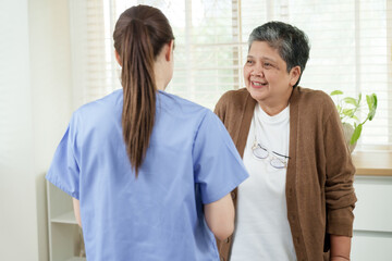 Obraz premium senior asian woman smiling and gently talking with young asian female physiotherapist during physical therapy session at home clinic focused on rehabilitation and elderly musculoskeletal treatment