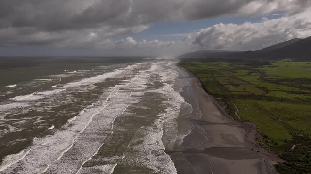 Dramatic coastline where Tasman Sea meets green landscape of Barrytown on New Zealand's West Coast. Aerial backward