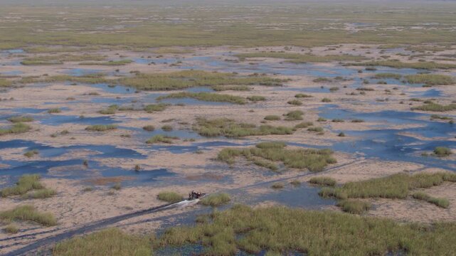 Dynamic aerial footage of an airboat racing through narrow sawgrass channels in the pristine Florida Everglades wetlands.