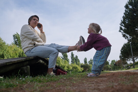 Seeking Attention: Toddler Girl Trying to Distract Her Mother from Smartphone in the Park