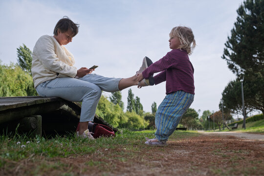 Seeking Attention: Toddler Girl Trying to Distract Her Mother from Smartphone in the Park
