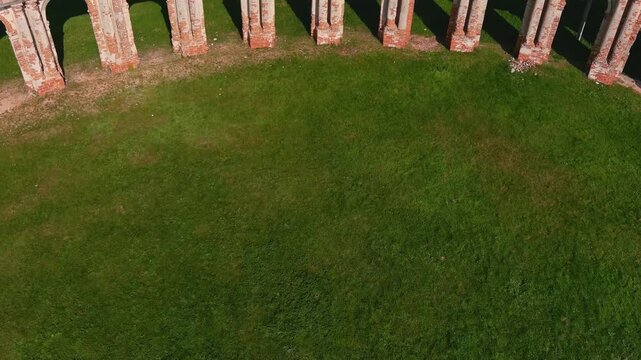 Ruined curved brick colonnade with arches at Ruzhany Palace in Belarus, a historic baroque arcade and abandoned heritage structure in a summer landscape