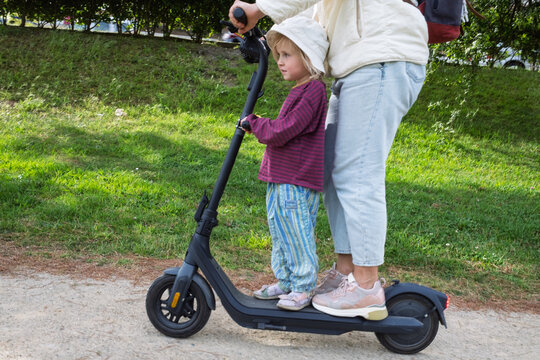 Unsafe Journey: Mother and Child Sharing an Electric Scooter at Speed on a City Pavement