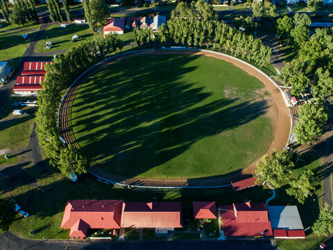 Buildings around Glen Innes Showground ring in bright sunlight from aerial view