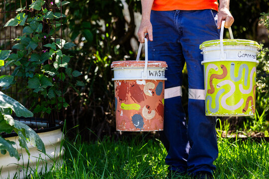 Australian person in backyard garden carrying buckets for food scraps to compost