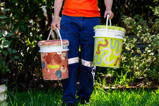 Australian person in backyard garden carrying buckets for food scraps to compost