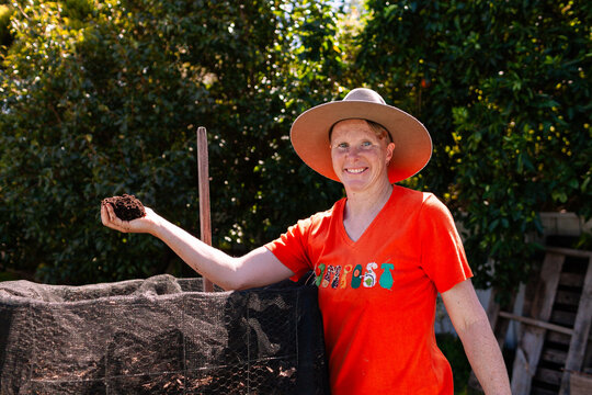 environmentalist composting advocate woman holding dirt made in garden compost system