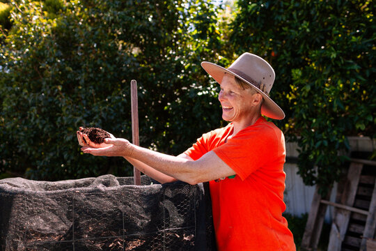 environmentalist composting advocate woman holding dirt made in garden compost system