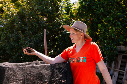 environmentalist composting advocate woman holding dirt made in garden compost system