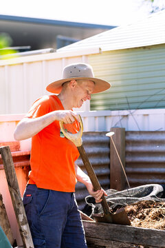 Australian woman in backyard garden ready to turn soil in compost container
