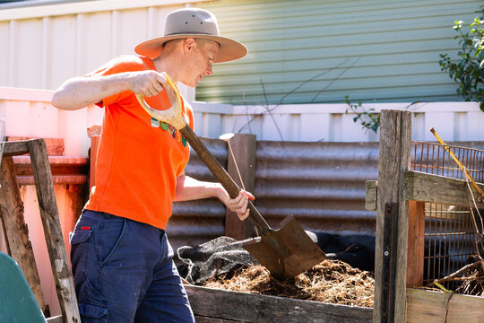 Australian woman in backyard garden ready to turn soil in compost container