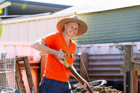 Australian woman in backyard garden ready to turn soil in compost container