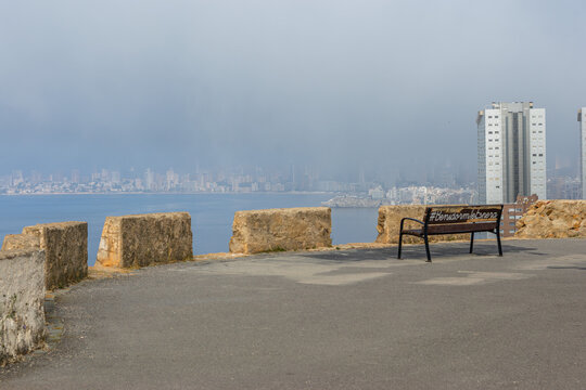 Wooden bench at a lookout point in Sierra Helada park, Spain. Quiet place for meditation and contemplating the Mediterranean Sea and Benidorm city skyline