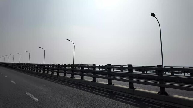 The sturdy concrete and metal bridge extends into the distance under a clear sky.