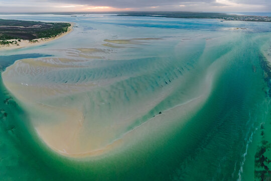 Aerial view of tidal channels and sand bars running through a shallow coastal bay