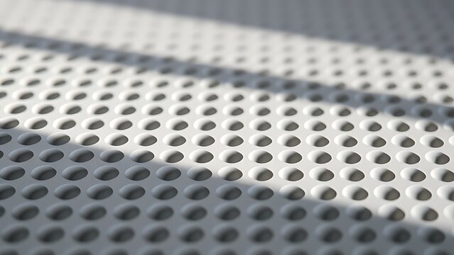 Grid of circular indentations on gray surface with side lighting.