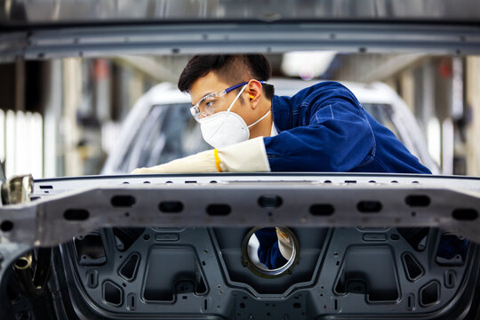 Asian workers are working on a car assembly line.