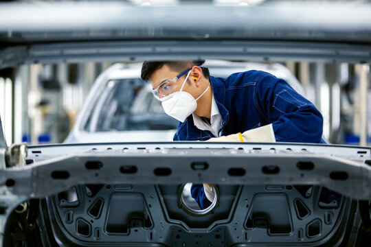 Asian workers are working on a car assembly line.