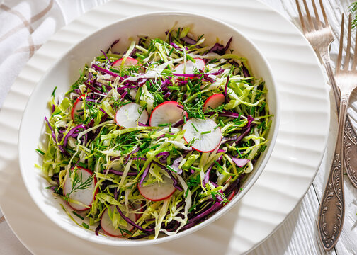 Fresh cabbage and radish coleslaw in white bowl