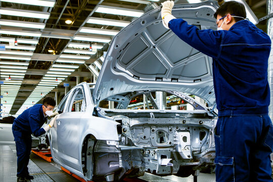 Two Asian workers are working on a car production line.