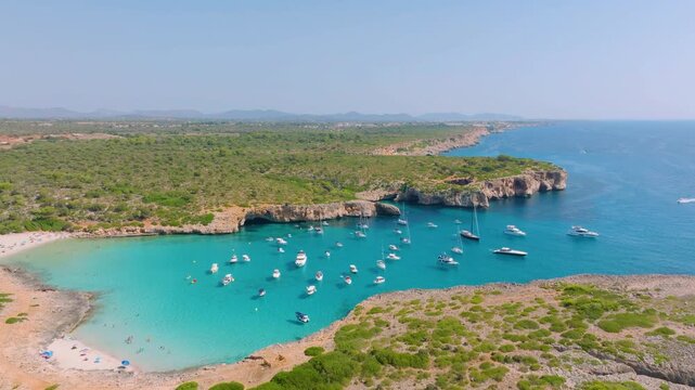 Aerial drone view of luxury yachts and boats in a turquoise bay with crystal clear water. Bright sunny summer landscape of a scenic coast and tropical beach.
