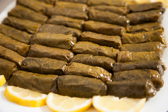 Close up of traditional stuffed grape leaves (dolma) served with lemon slices. Mediterranean Greek cuisine appetizer with detailed texture.