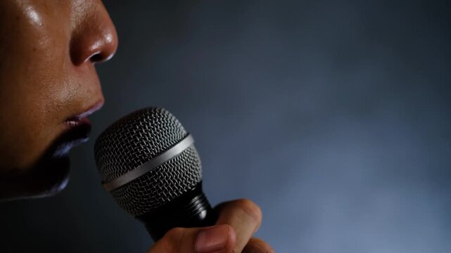 Happy Asian male singer holding a microphone and singing performance.