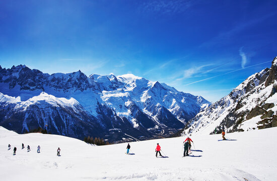 Skiers in the Chamonix Valley, with a prominent view of the Mont Blanc massif in the background.