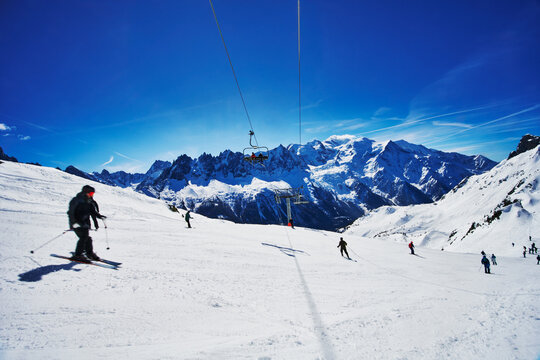 Skiers in the Chamonix Valley, with a prominent view of the Mont Blanc massif in the background.