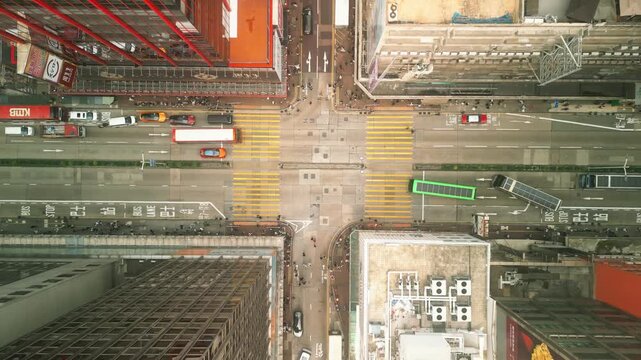 Top down drone view of busy city intersection with traffic and crosswalks in Hong Kong