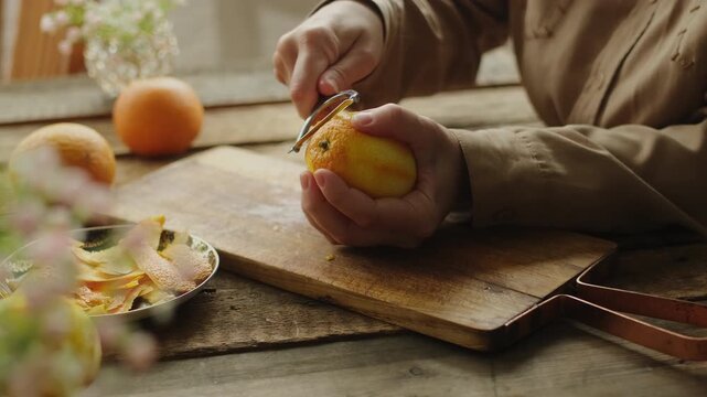 Female hands peeling fresh orange zest