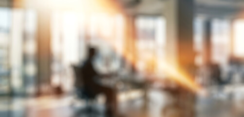 Obraz premium An abstract representation of a modern office environment with silhouettes of people working at their desks. Soft focus creates a dynamic ambiance.