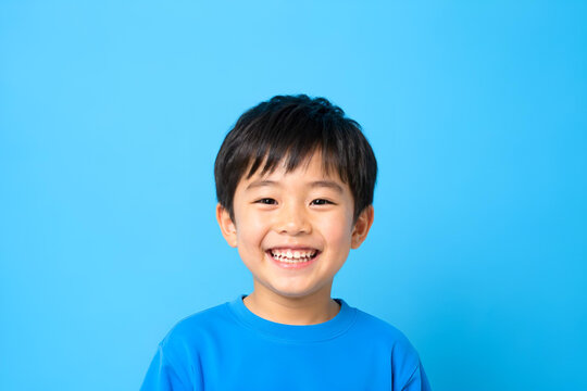 こどもの日に使える歯が見える笑顔の日本人男の子ポートレート ビビッド単色背景 コピースペース 明るい子供イメージ -生成AI
