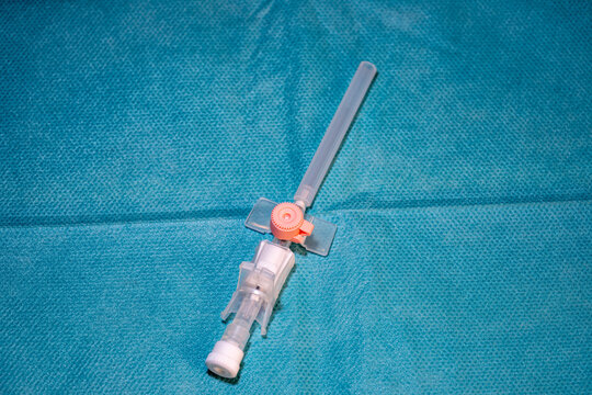 Medical IV cannula peripheral venous catheter on blue sterile surgical background