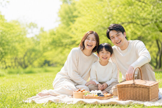 ゴールデンウィークの新緑公園でピクニックする笑顔の日本人家族 ライフスタイル写真 旅行レジャーイメージ コピースペース -生成AI