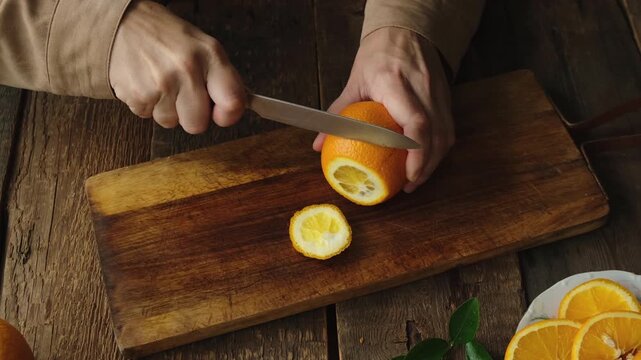 Woman slicing fresh oranges on wooden cutting board. Preparing citrus fruits for mulled wine or lemonade