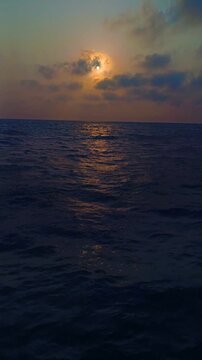 Golden sunset over the open ocean with dramatic clouds and gentle waves