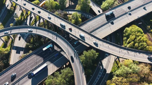 Top-down aerial drone footage rotating and tracking moving traffic across a complex multi-level motorway interchange in Birmingham, United Kingdom. Vehicles flow through interconnected highways