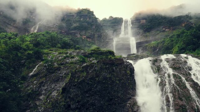 Kynrem Waterfall cascading down towering cliffs through mist and rainforest in Meghalaya India